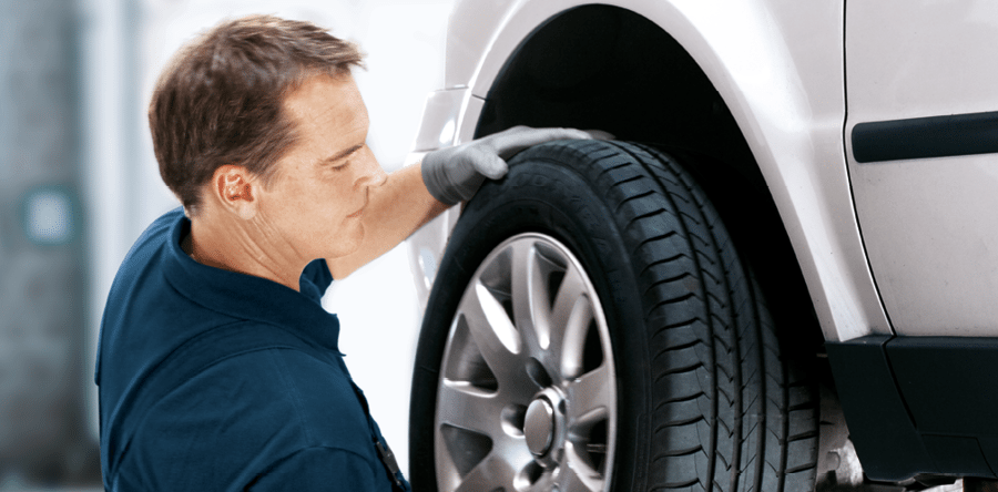 Een monteur wisselt een wiel met band aan een auto